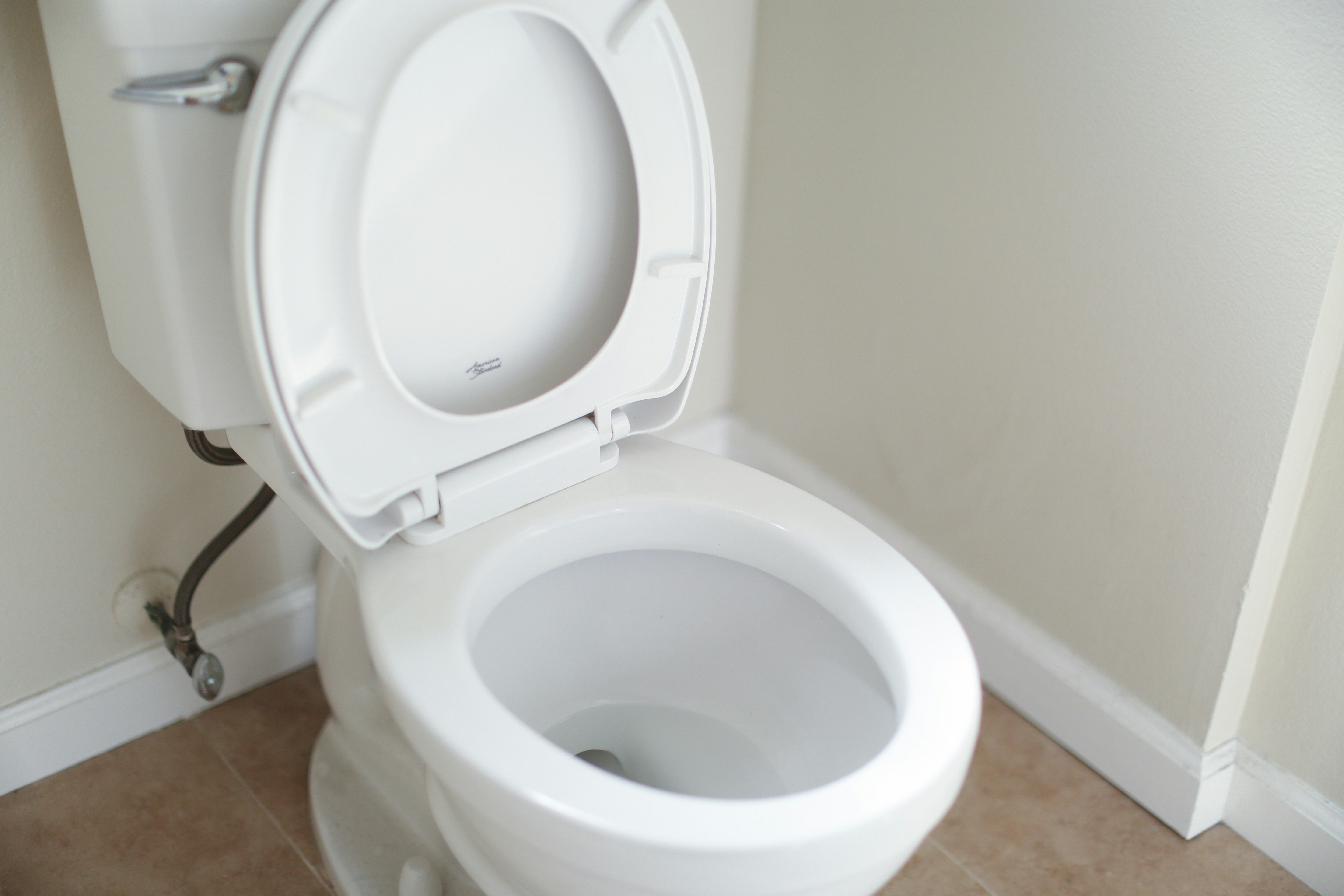 Open white toilet in a clean residential bathroom corner.