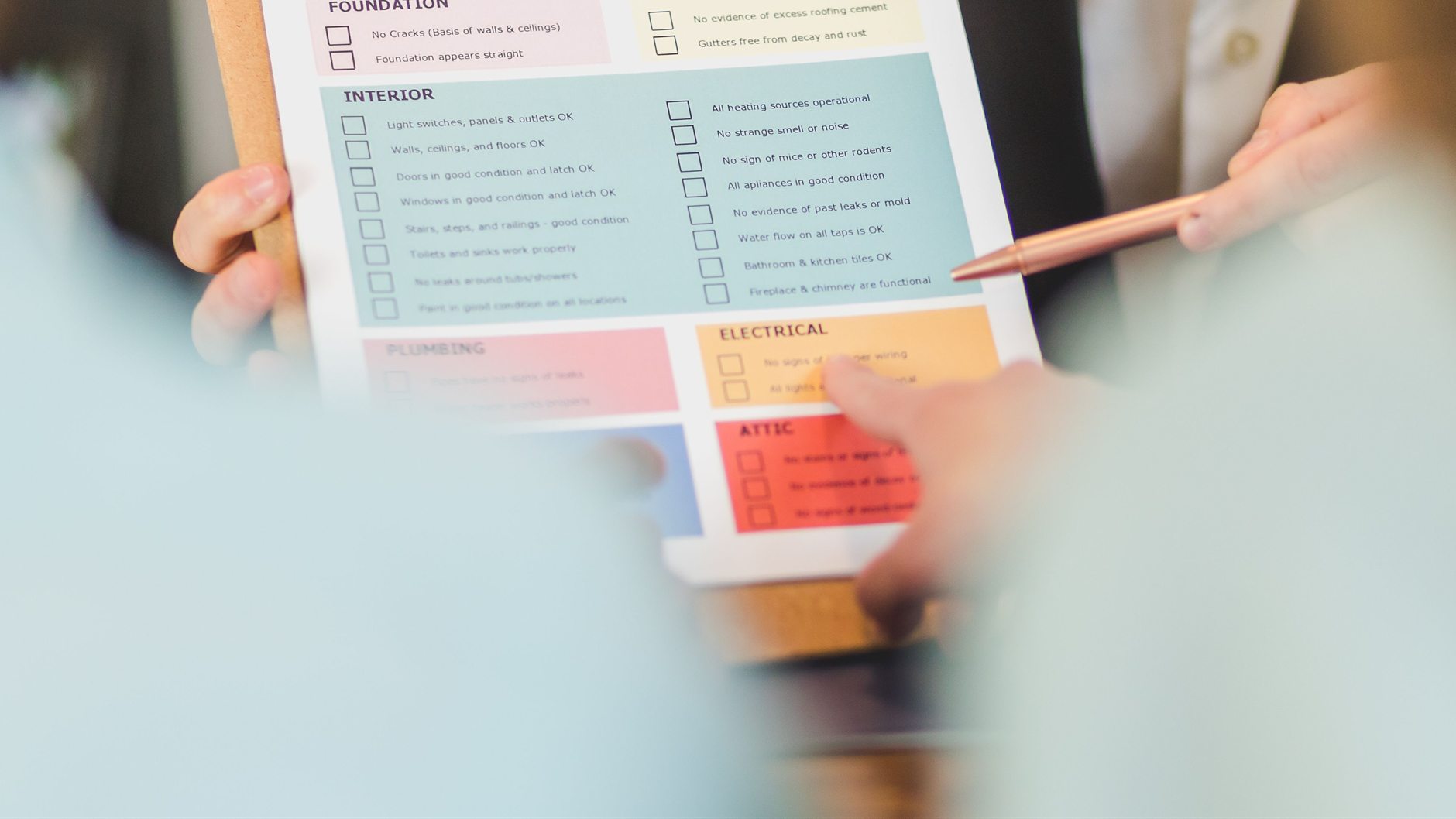 Hands reviewing a home inspection checklist inside a residence.