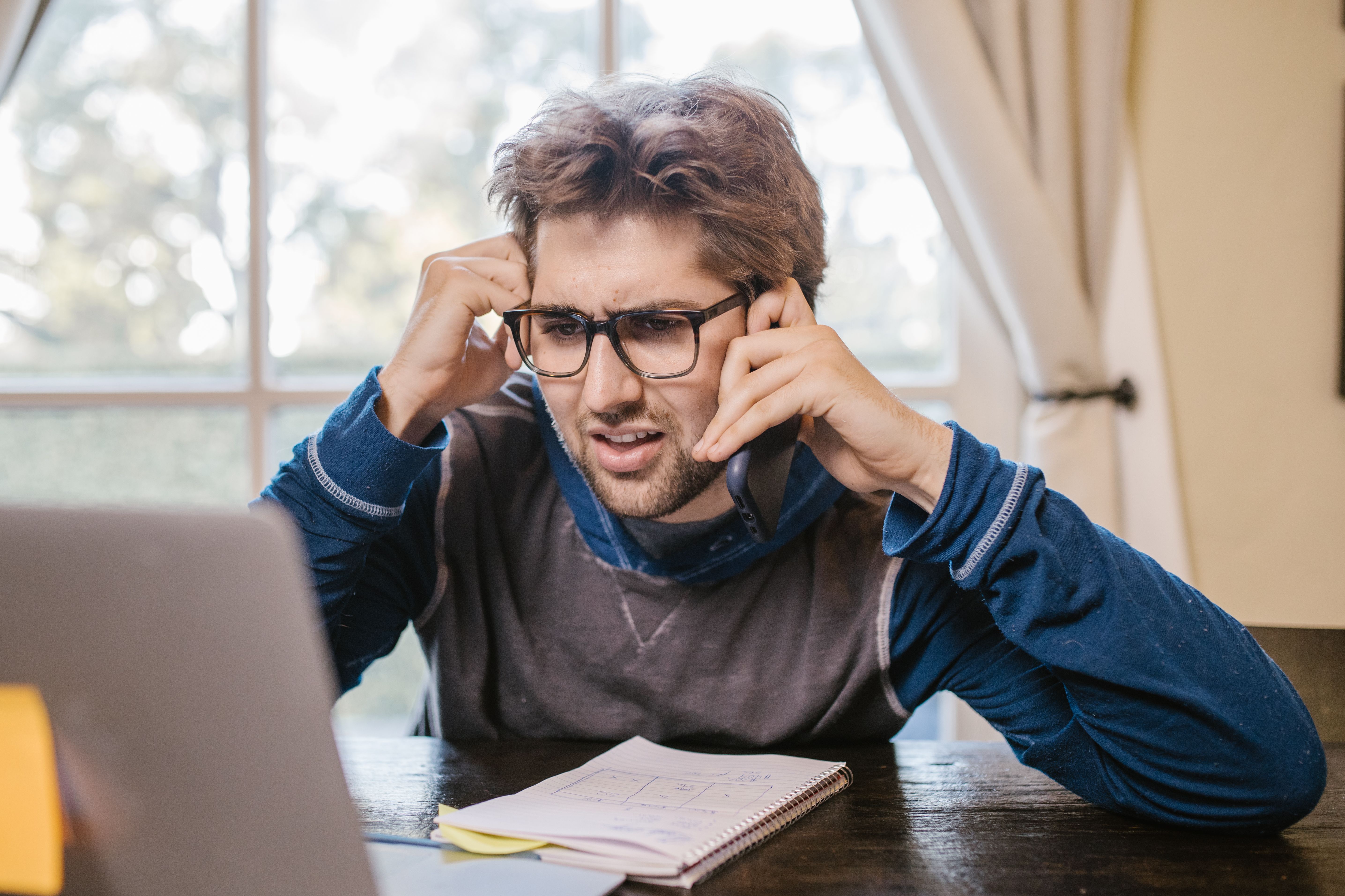 A confused man searching for renovation information on his laptop at home, frustrated by unclear online results.