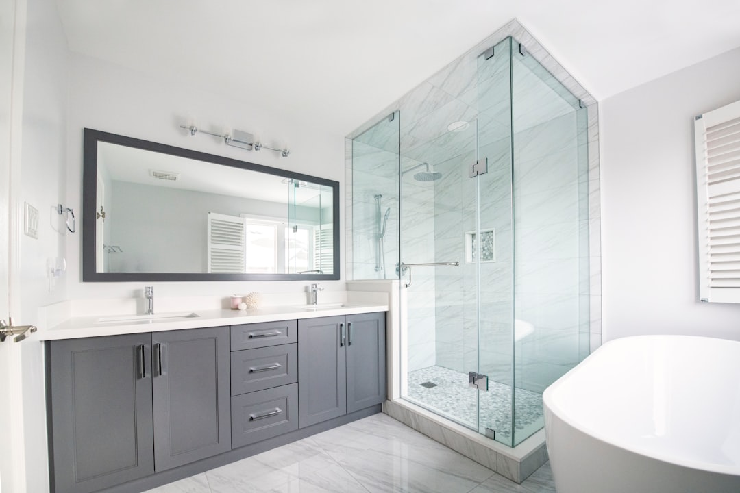 Modern renovated bathroom with glass-enclosed shower, freestanding tub, and gray double vanity