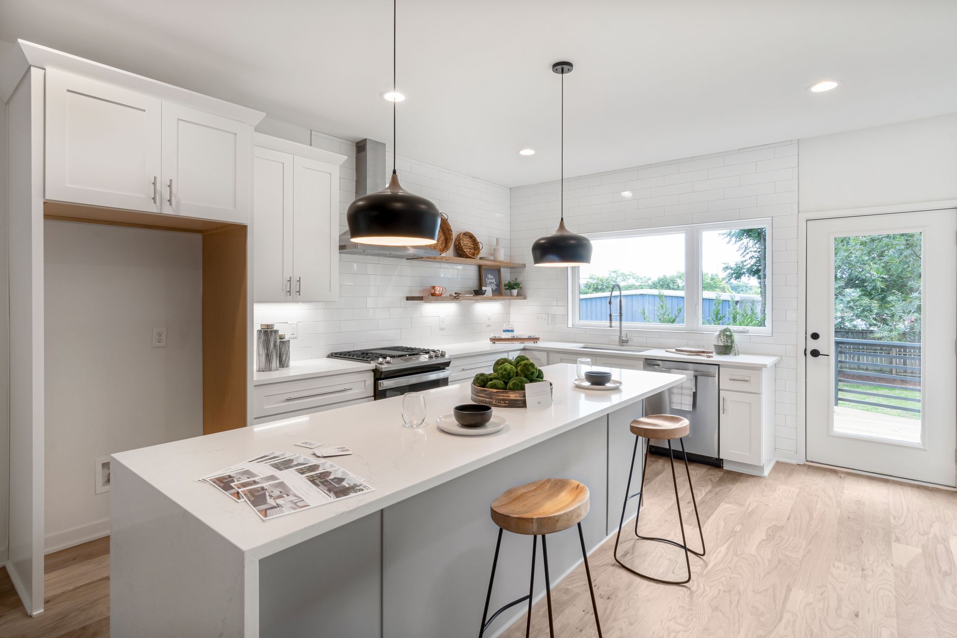 White kitchen with an island, quartz-look counters, wood bar stools, and pendant lighting