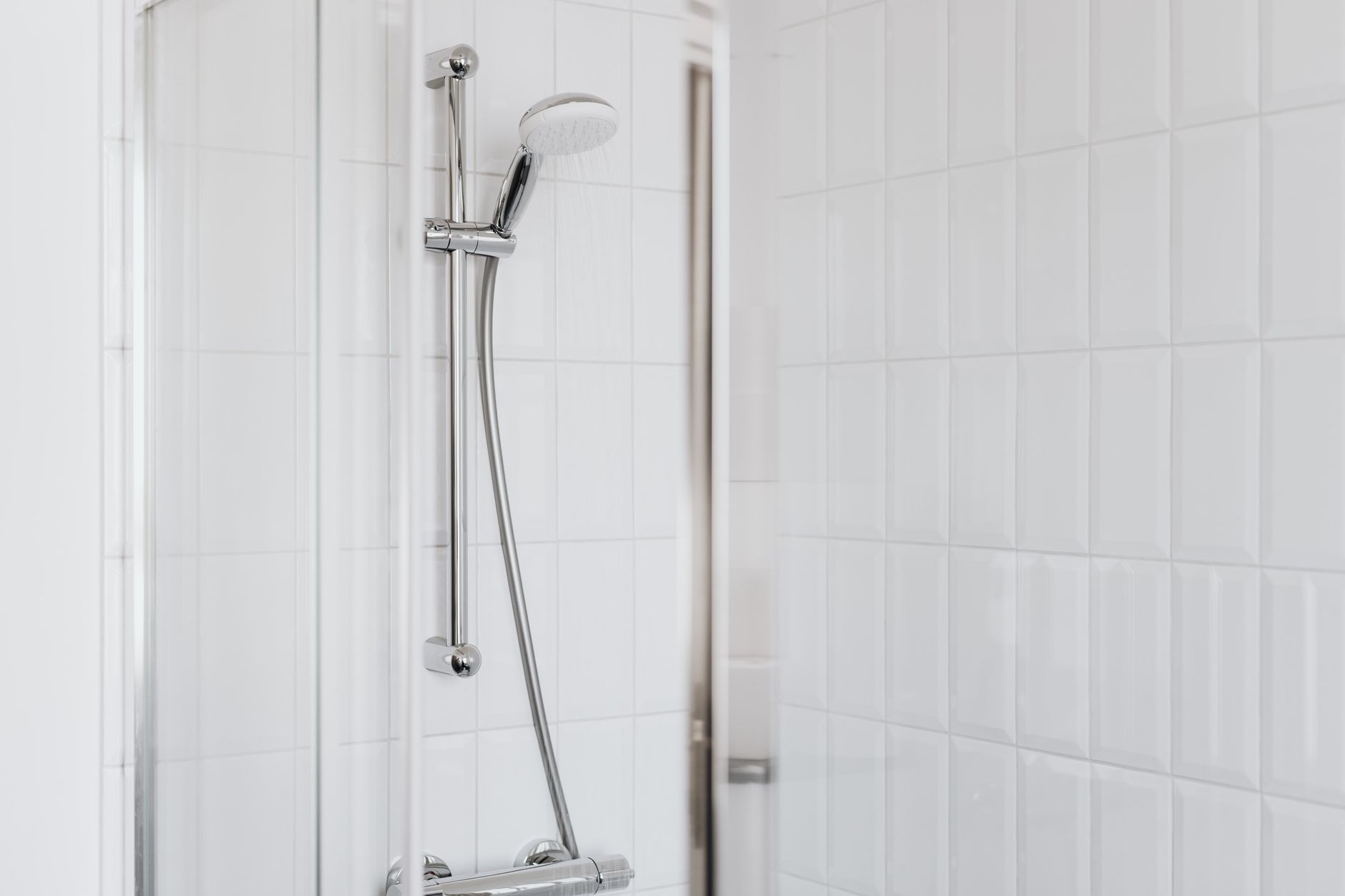 Stylish modern shower setup with chrome fixtures and clean white tiles