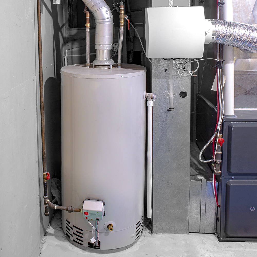 Gas-fired water heater tank installed in a basement utility room next to a furnace, with metal flue venting and a gas control valve visible