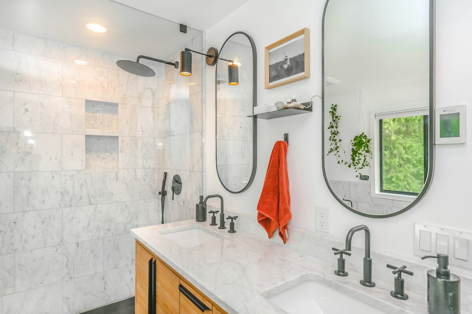 A bright, newly renovated Vancouver bathroom with a marble-tiled walk-in shower and double vanity