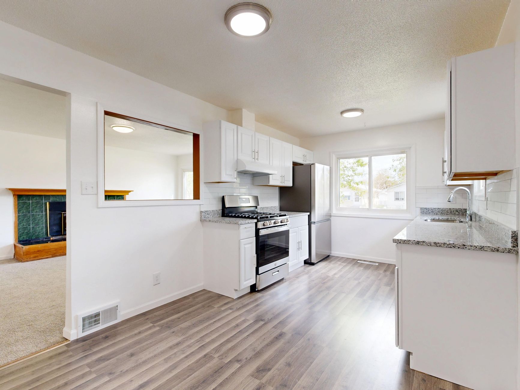 A beautiful, modern open-concept kitchen with clean lines, white countertops, and warm wooden accents.